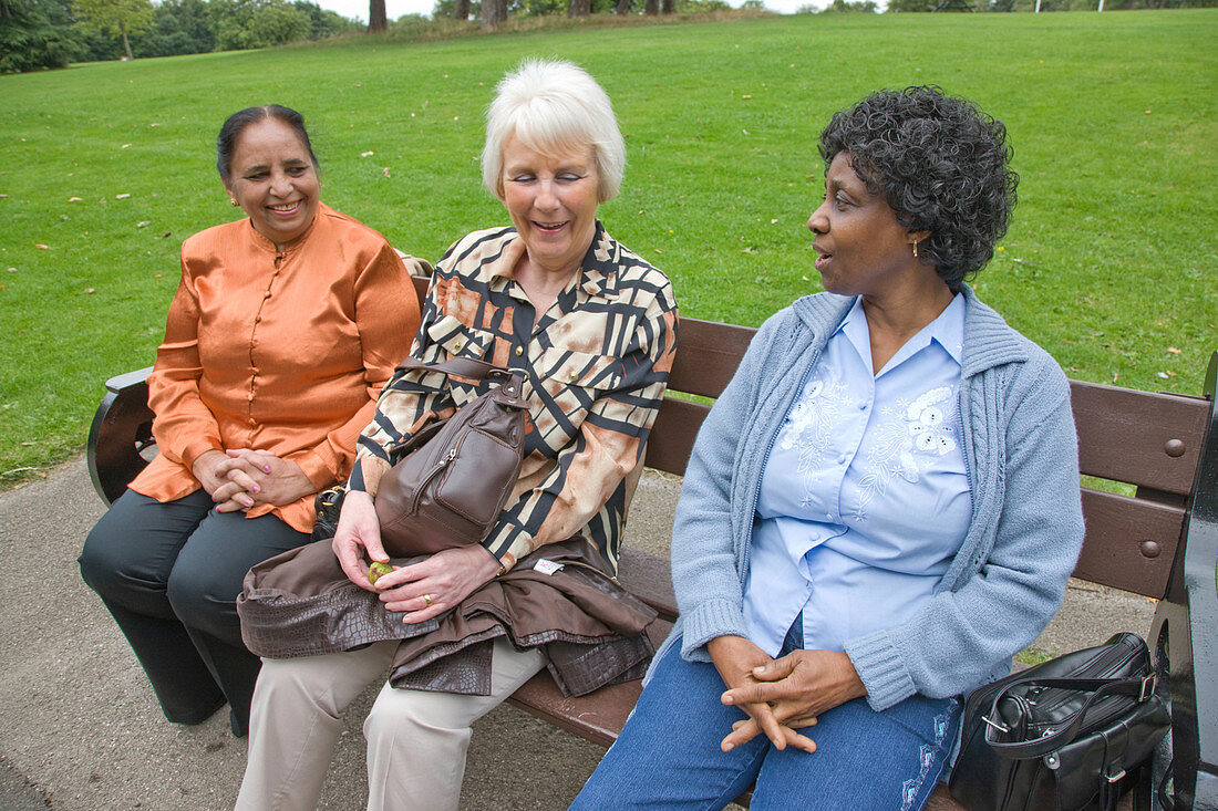 Group of older woman sitting on bench in the park chatting