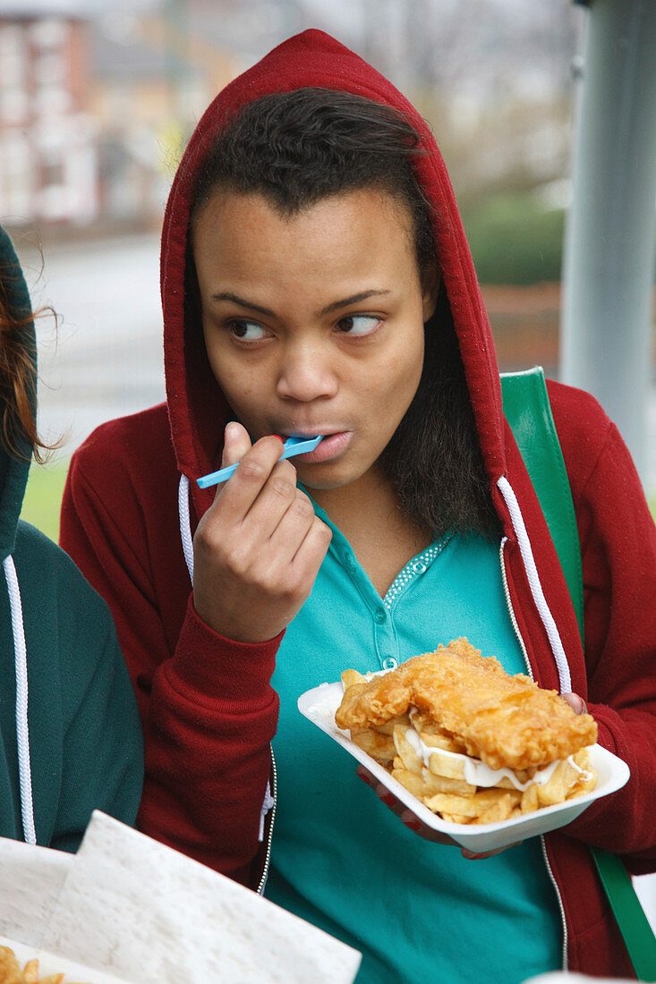 Teenage girl eating fish and chips