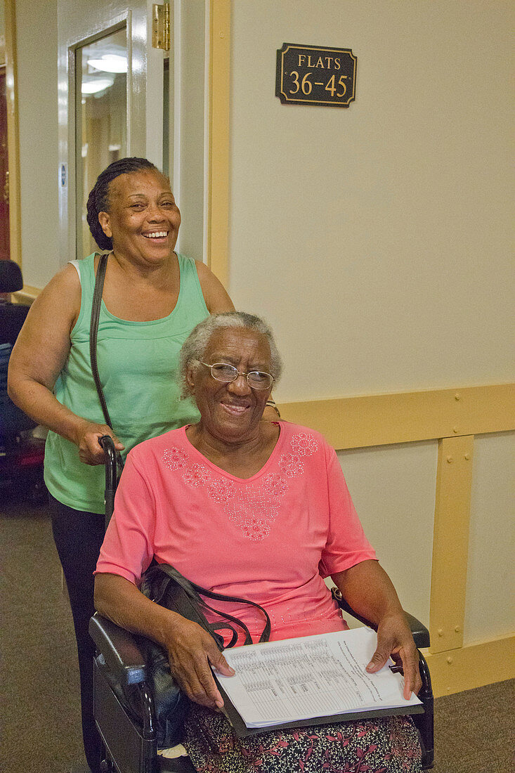 Carer pushing elderly visually impaired woman