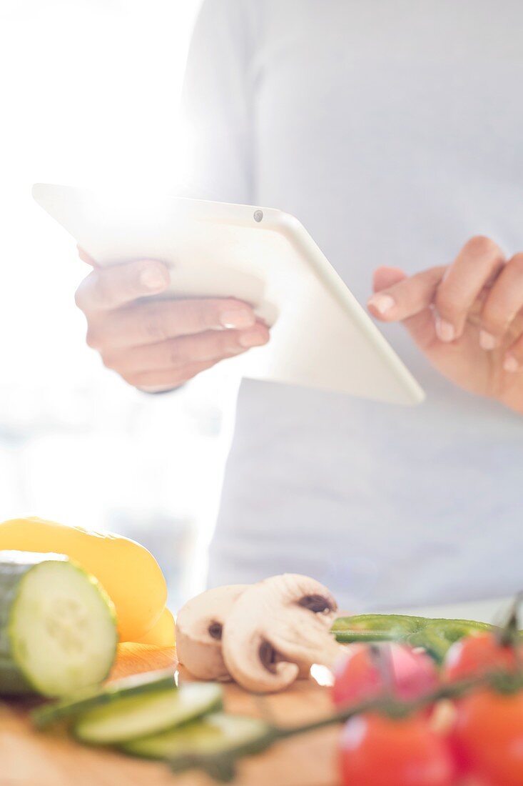 Woman preparing food using digital tablet