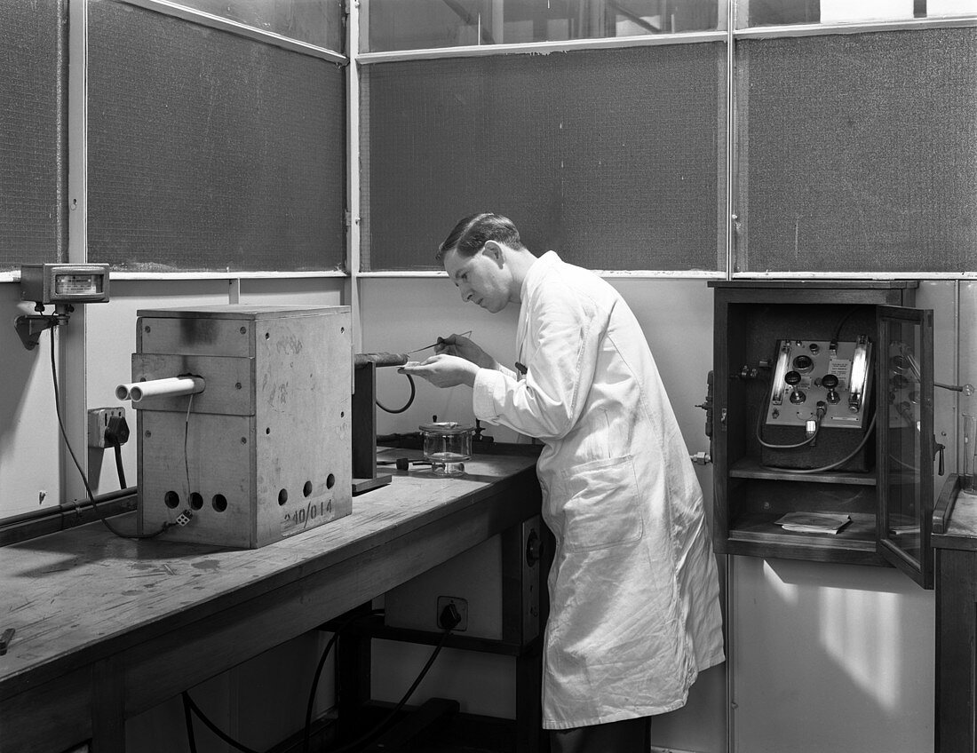Lab technician using a table top test furnace, 1962