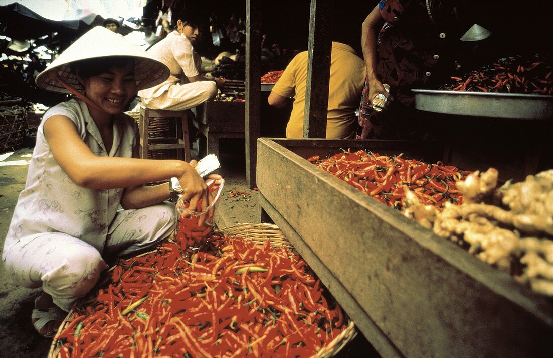 Asiatin füllt Chilischoten in eine Tüte auf dem Markt