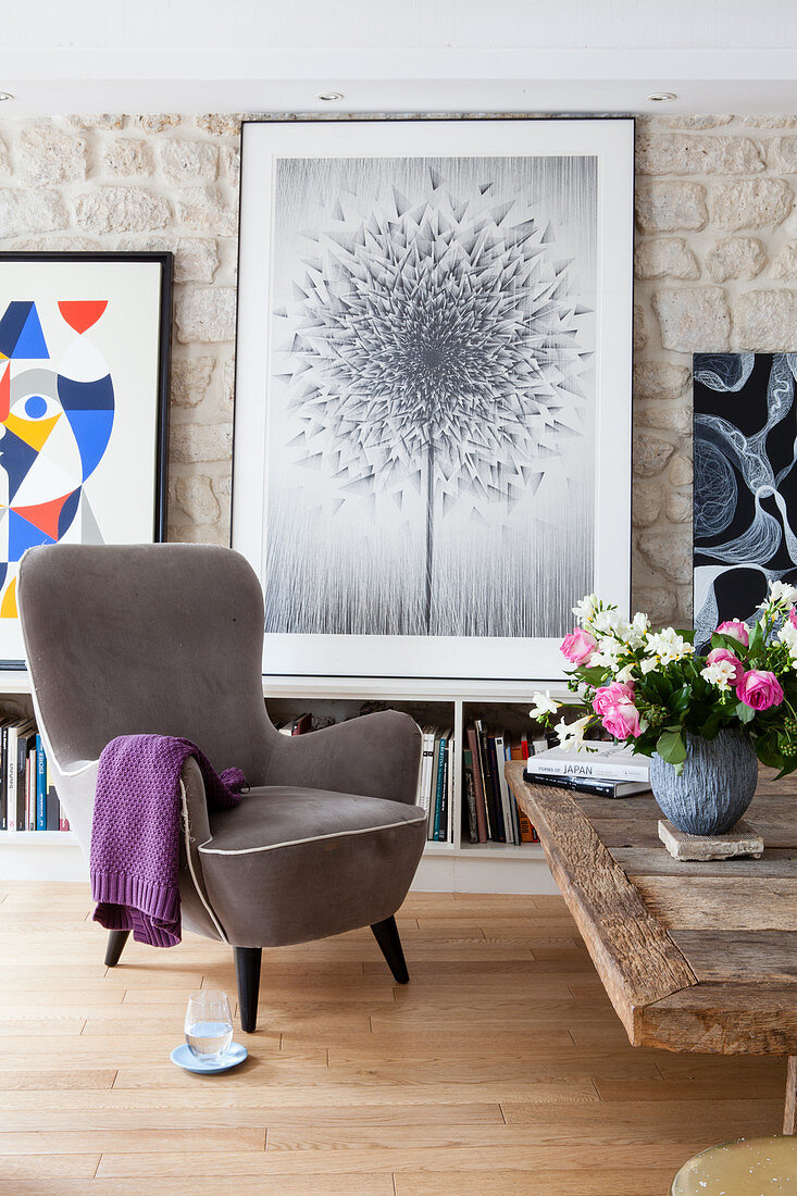 Grauer Sessel vor dem Bild einer Pusteblume im Wohnzimmer