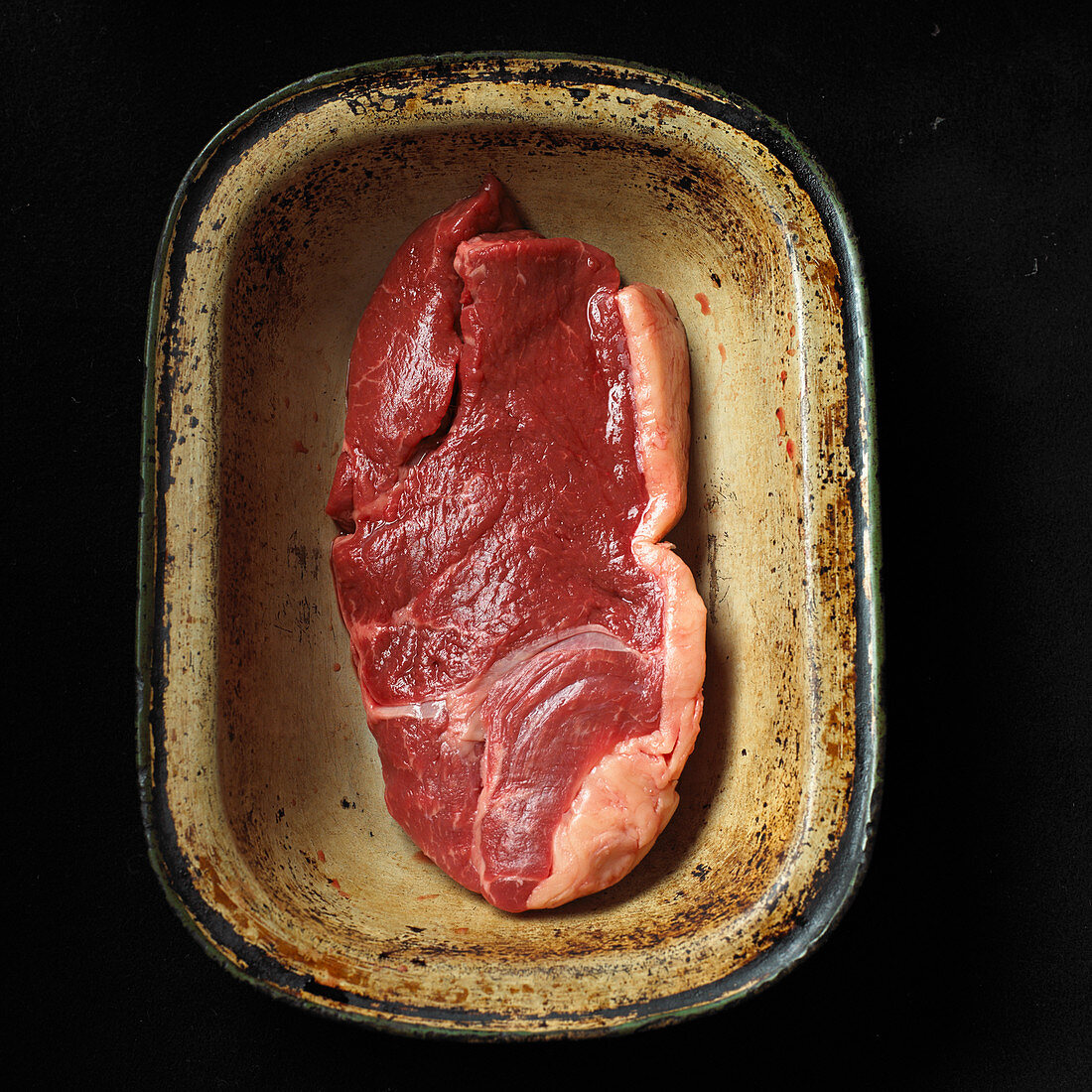 Raw beef steak in an old roasting dish