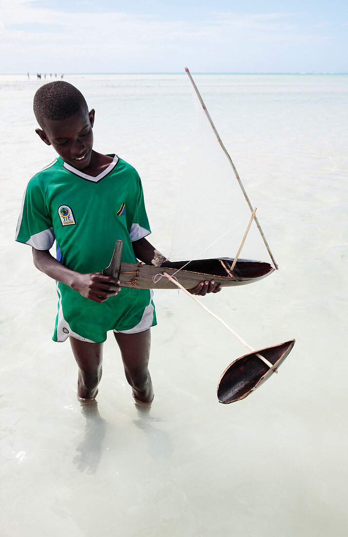 Boy with a toy boat on a beach, Zanzibar