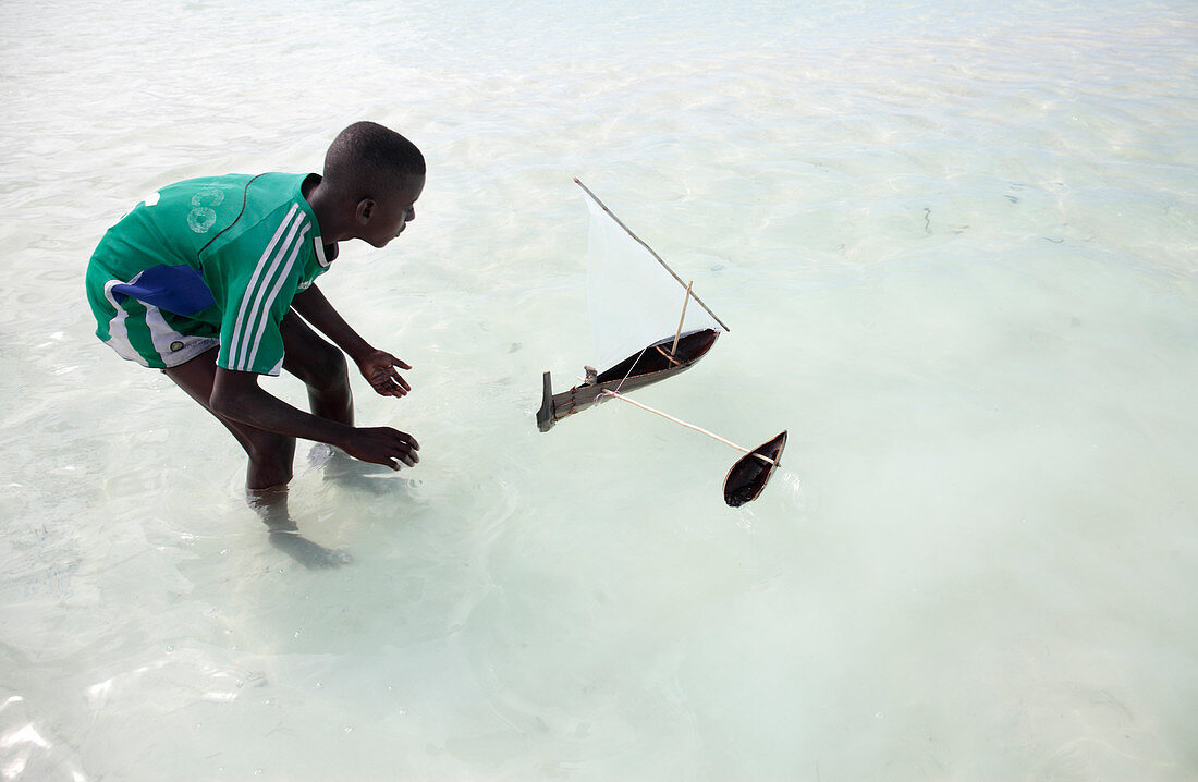 Boy with a toy boat on a beach, Zanzibar