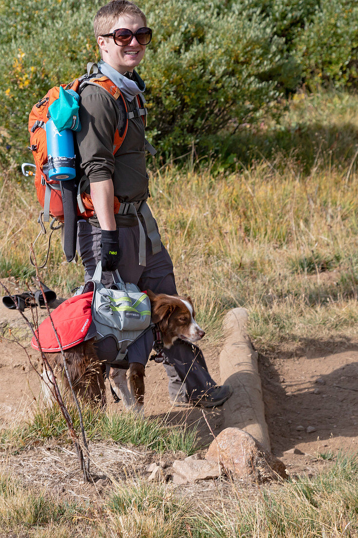 Hiker carrying dog on a hiking trail