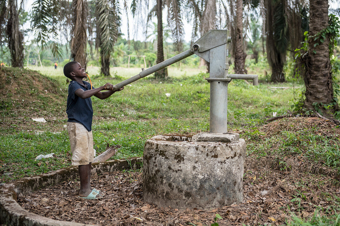 Young children pumping water from a well, Ganta, Liberia