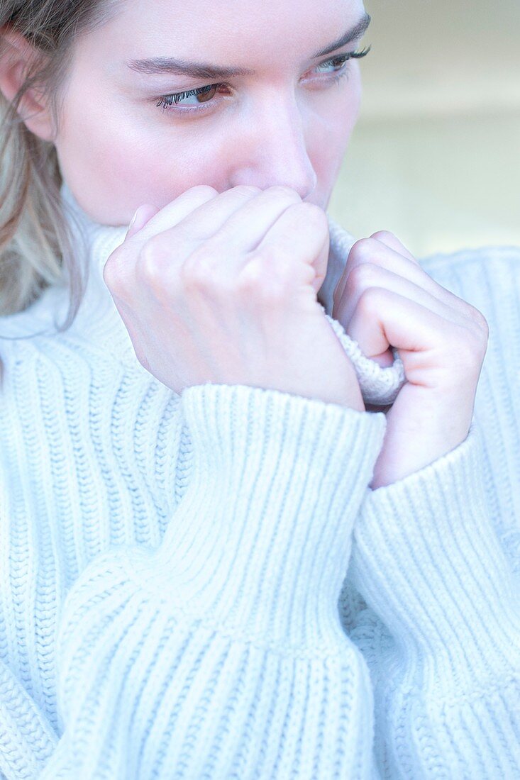 Young woman clasping neck of sweater