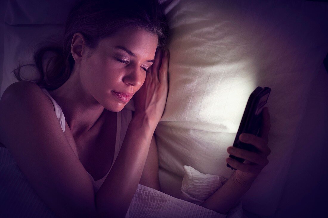 Young woman falling asleep with smartphone