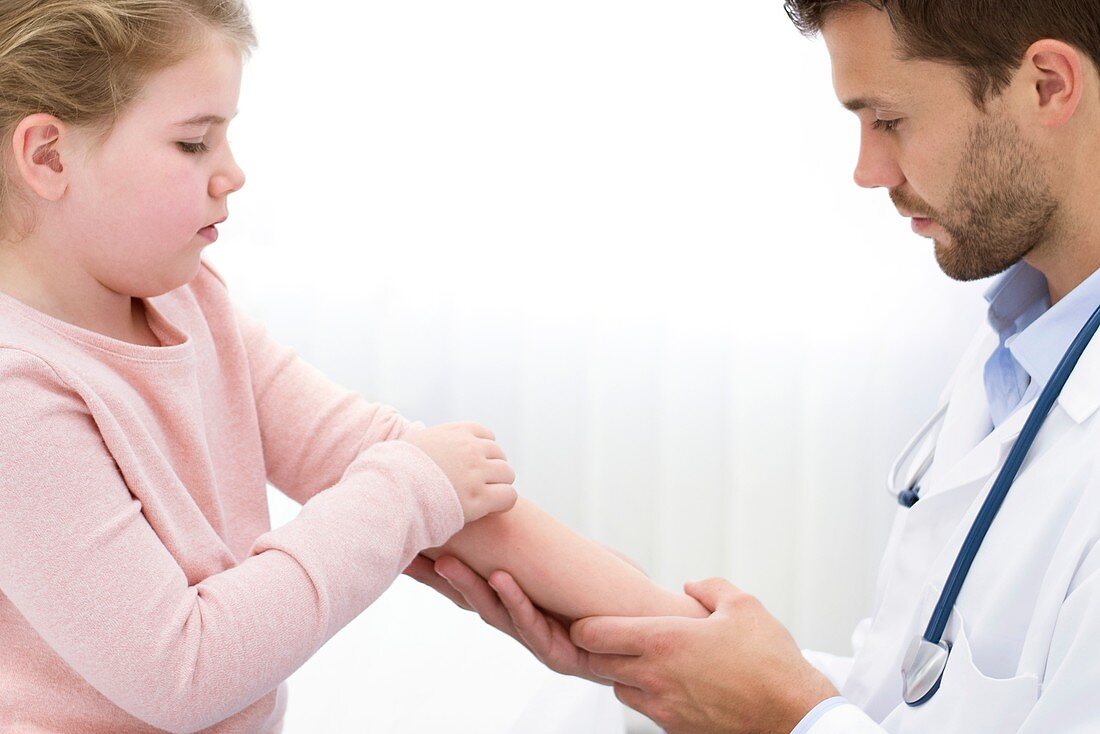 Doctor examining girl's arm