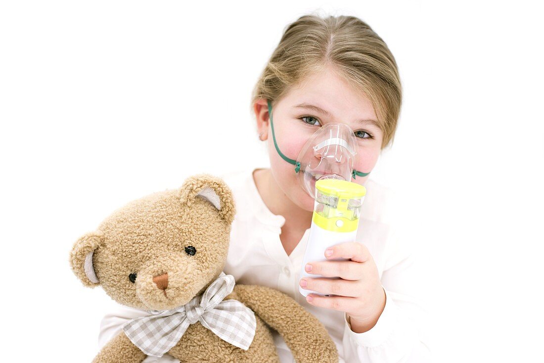 Girl using nebuliser holding teddy bear