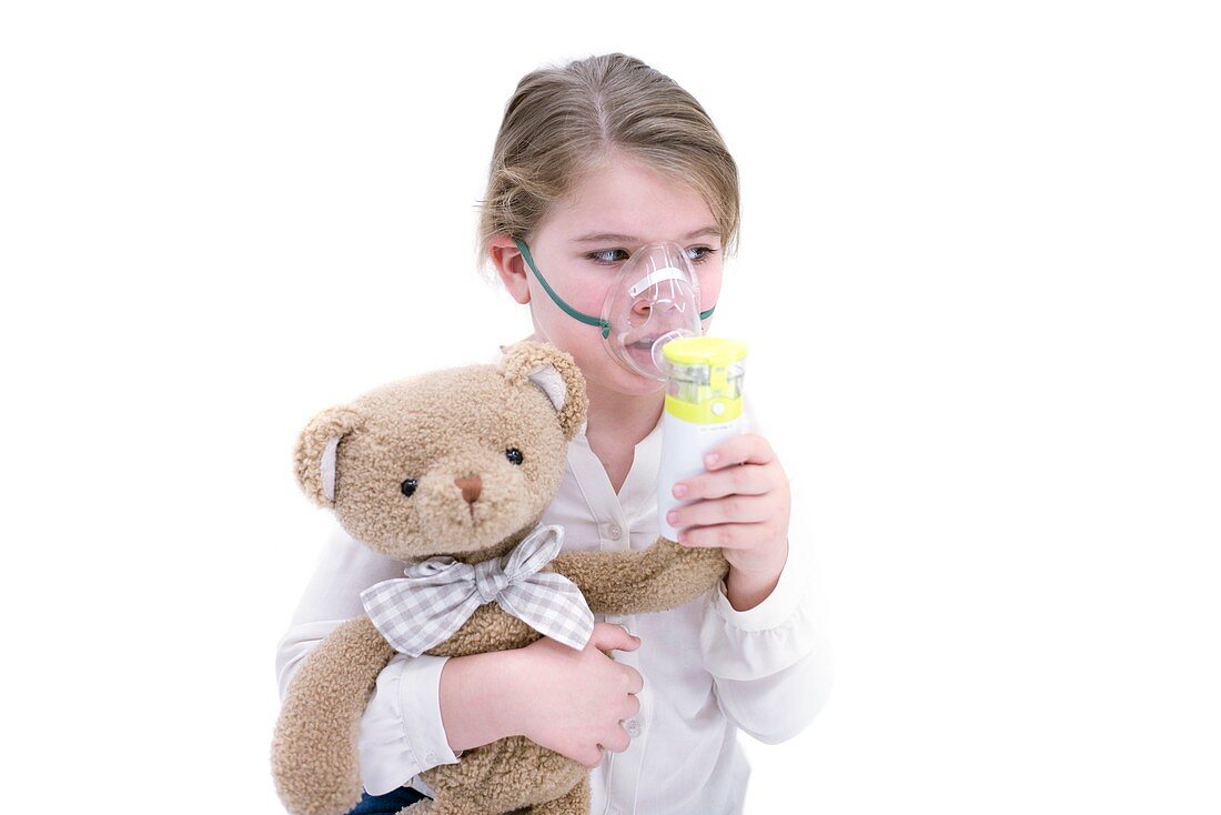 Girl using nebuliser holding teddy bear