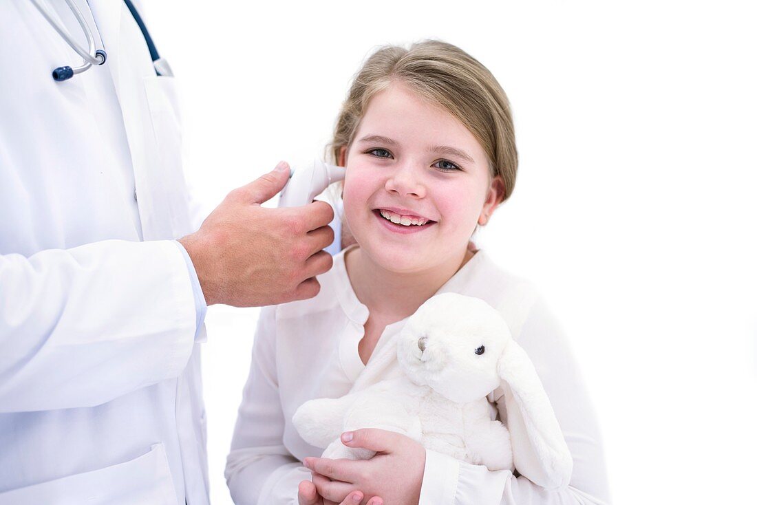Doctor taking girl's temperature using thermometer