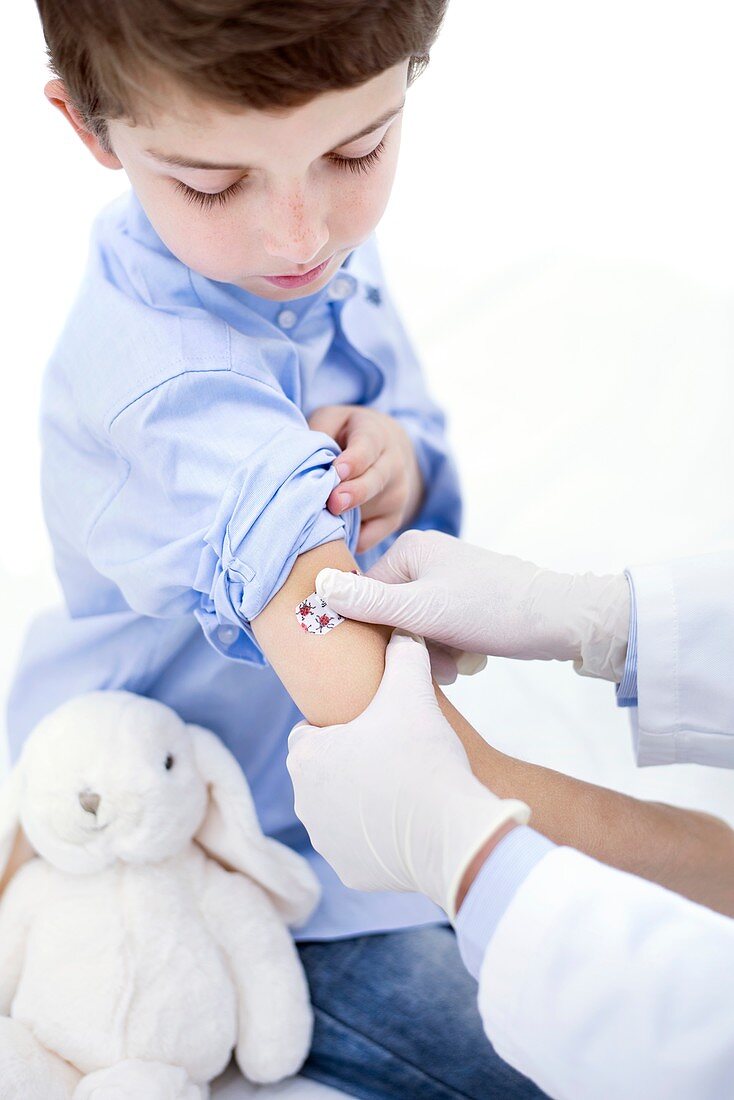 Doctor putting plaster on boy's arm
