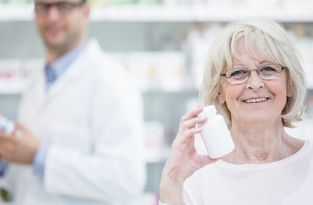 Senior woman holding pill bottle in pharmacy