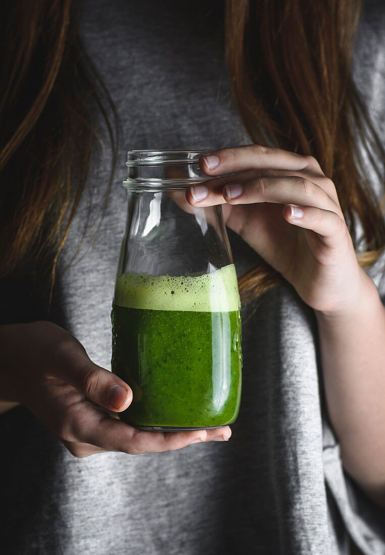 Women holding a jar with spinach smoothie