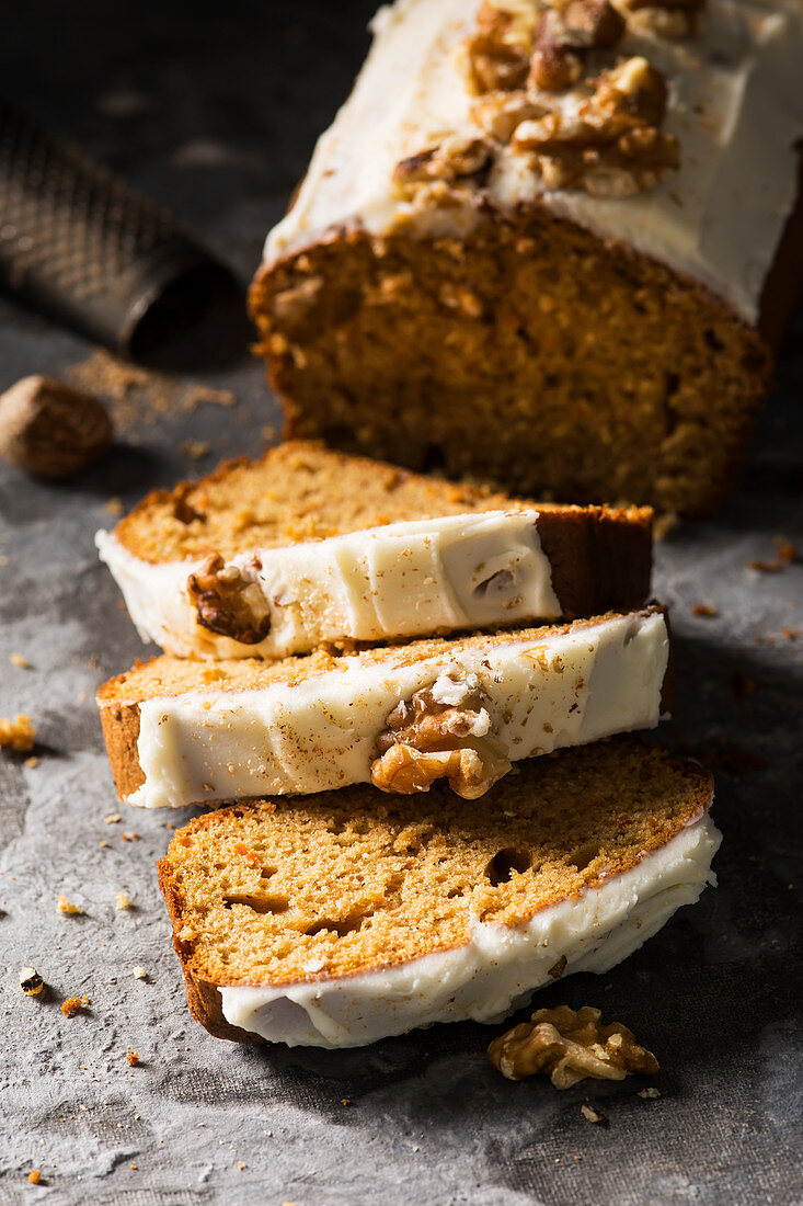 Carrot loaf cake sliced with nutmeg and grater in background