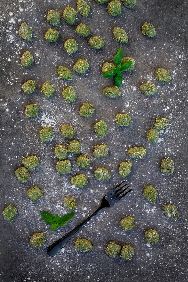 Frische Spinat-Basilikum-Gnocchi auf grauem Untergrund (Aufsicht)