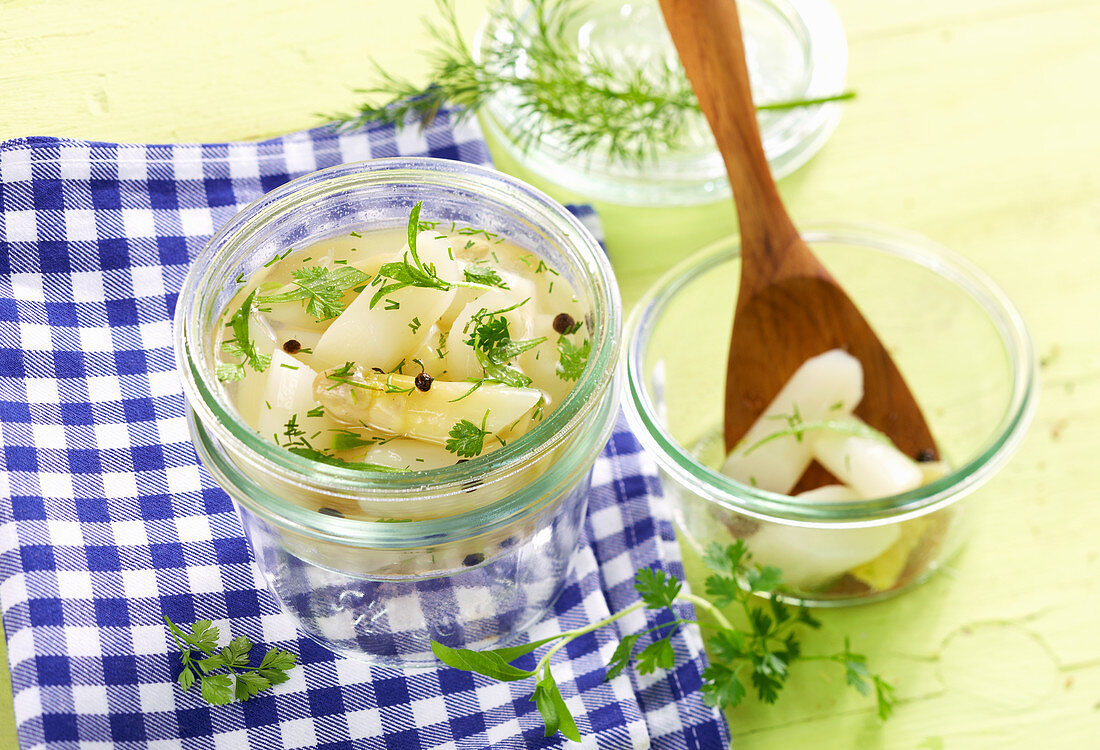 White asparagus in a herb marinade with sugar, vinegar and fresh herbs in jars