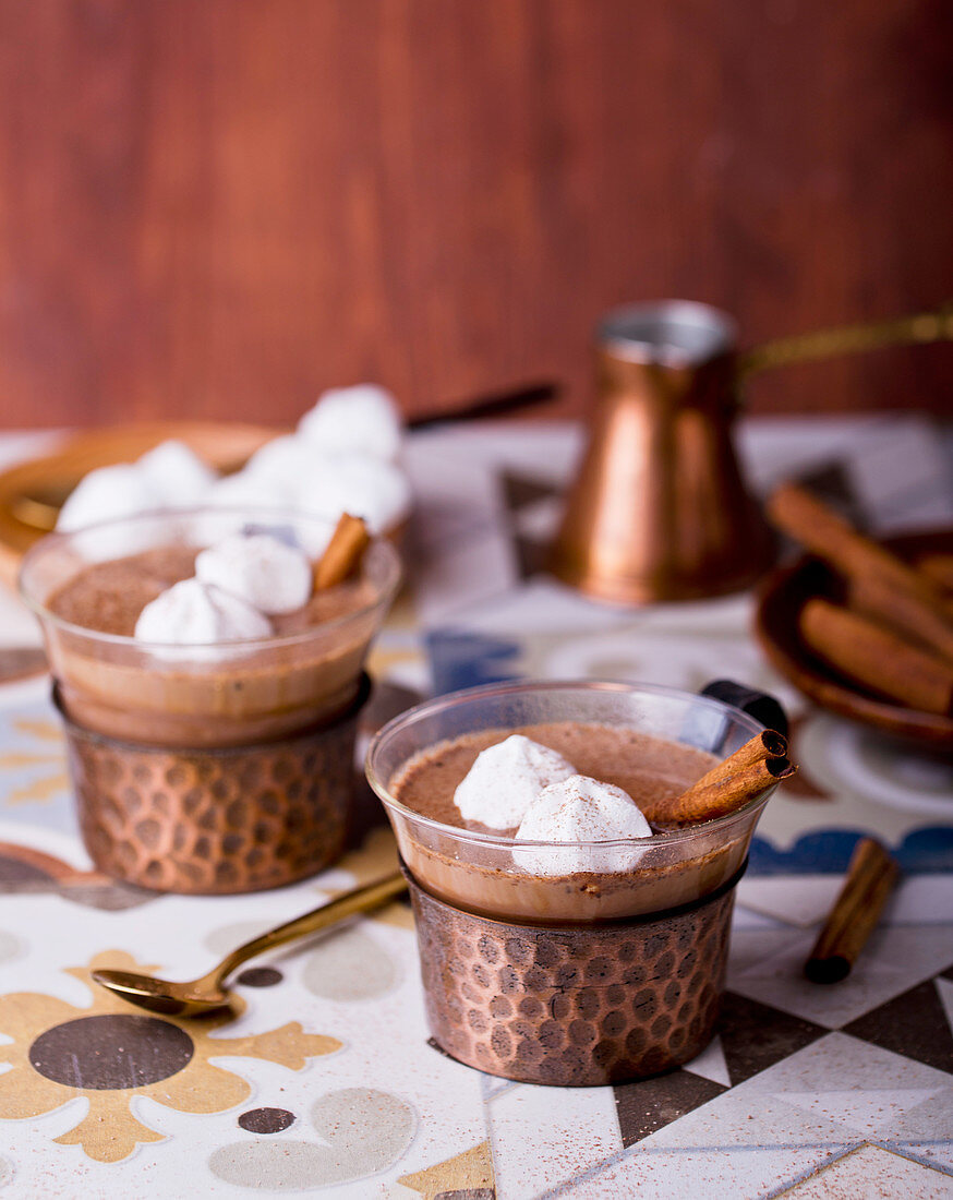 Hot chocolate garnished with meringue dots and cinnamon sticks