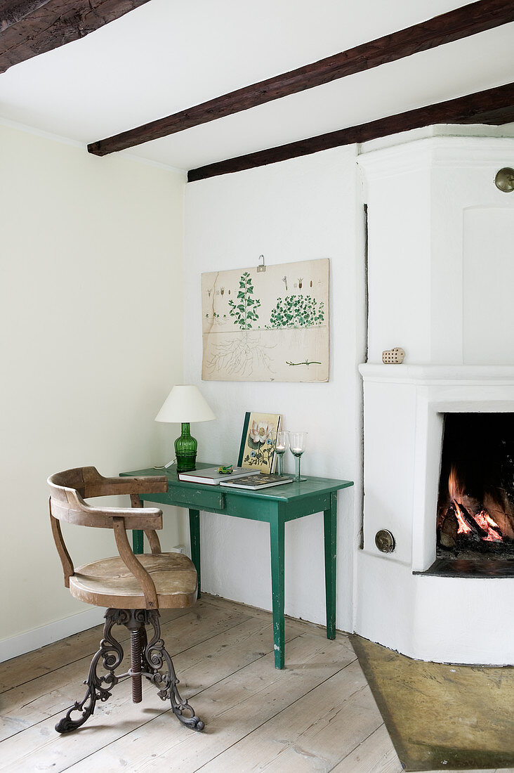 Old chair at green table next to fireplace