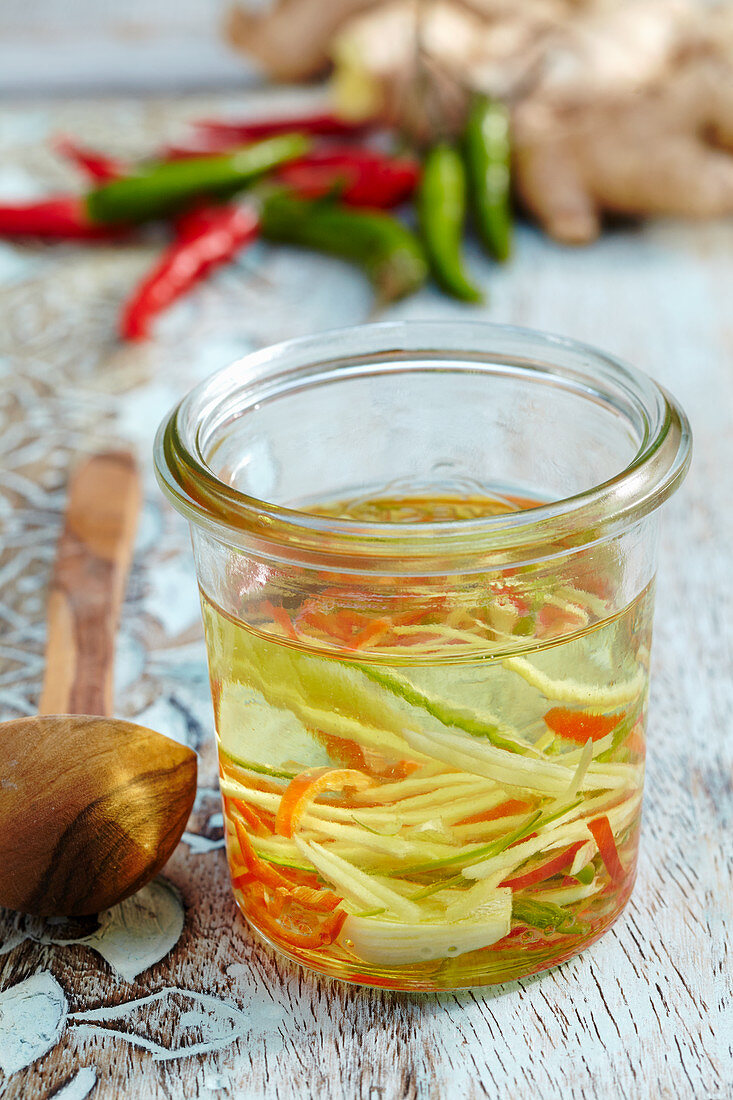 Herb oil with fresh chillies, ginger, and garlic in a mason jar