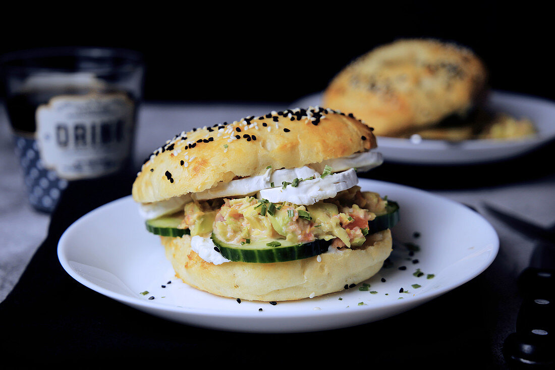 A sesame seed bagel sandwich with cucumber and cream cheese