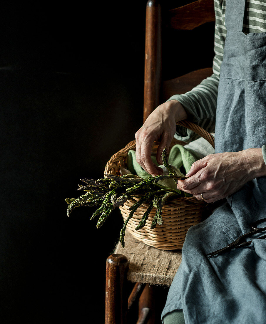 Female sitting on chair with basket of wild asparagus