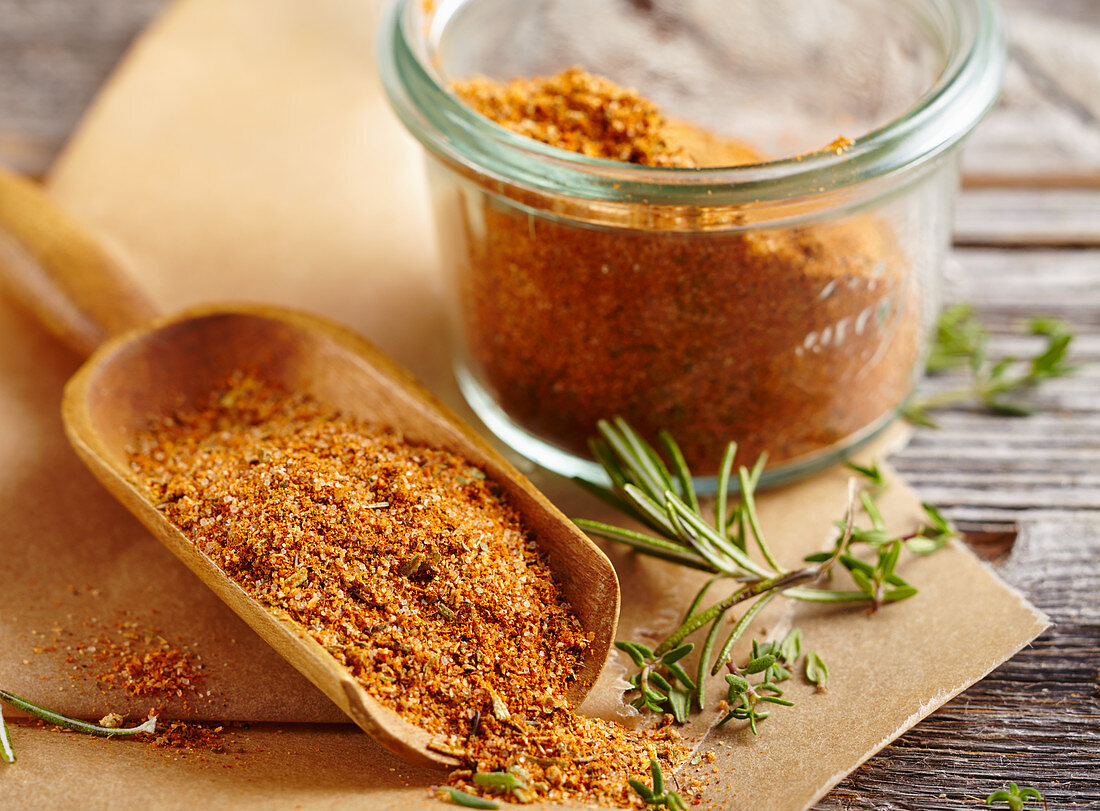 Homemade steak spice mix in a glass and on a wooden scoop