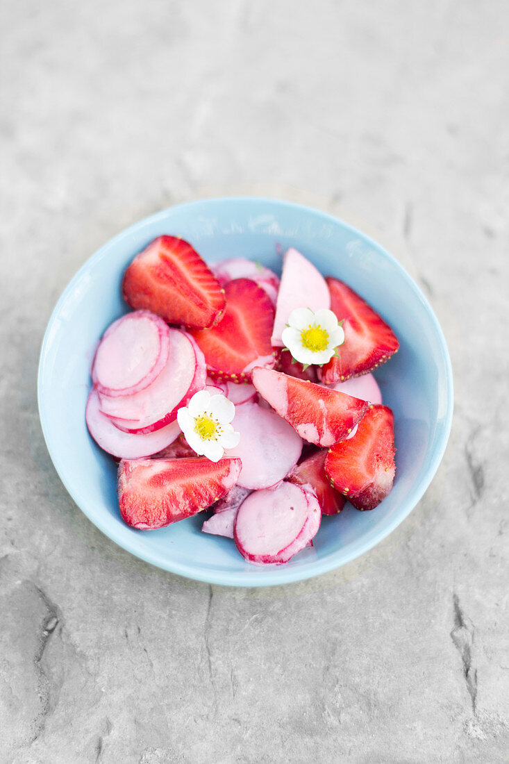 Strawberry and radish salad, drizzled with yoghurt dressing and garnished with strawberry flowers