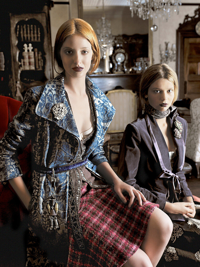 Two young women wearing skirts and jackets in a home setting