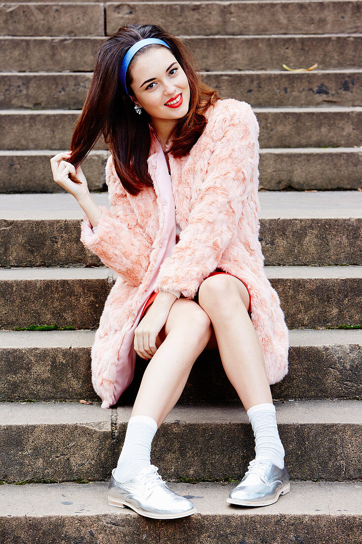 A young brunette woman wearing a pink woollen coat