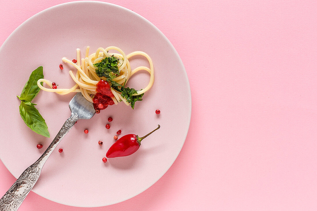 Spaghetti mit Tomatensauce und Pesto auf rosa Teller