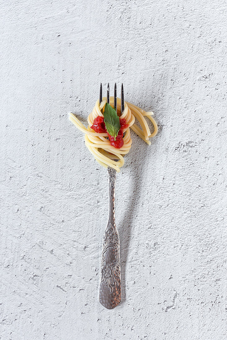 Spaghetti mit Tomatensauce auf Gabel vor weißem Hintergrund