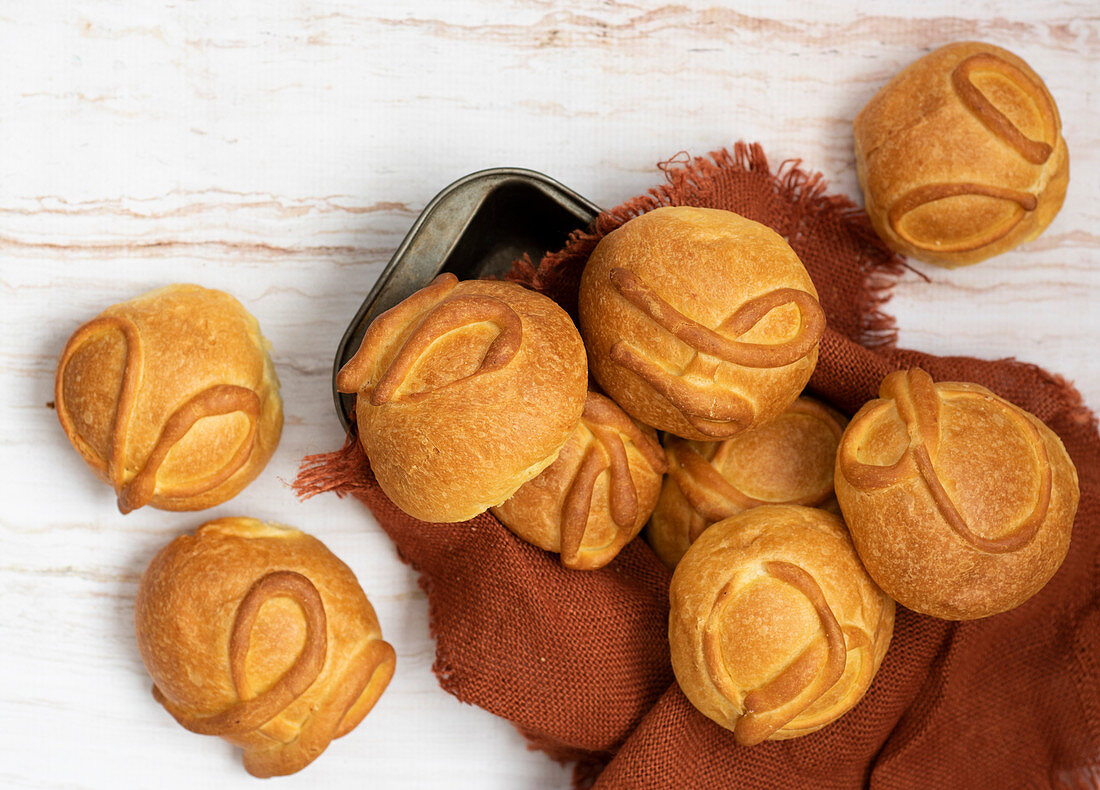 Baked round buns laid on brown napkin on wooden background
