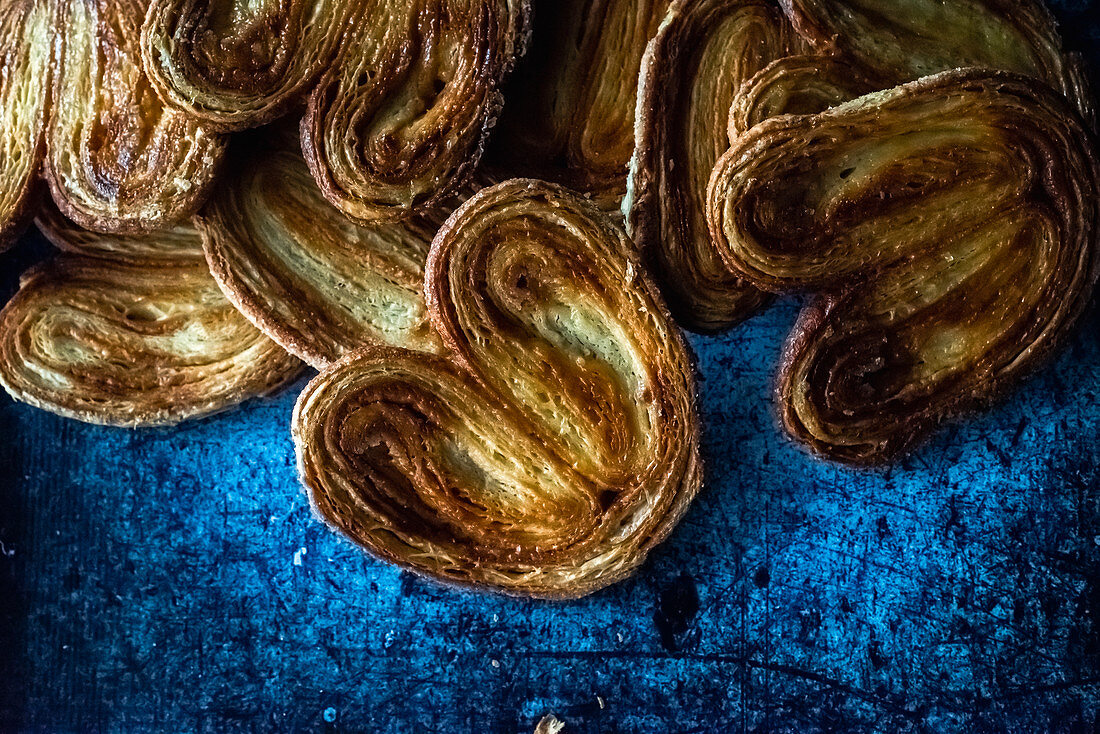 Palmier cookies laid in pile on blue background