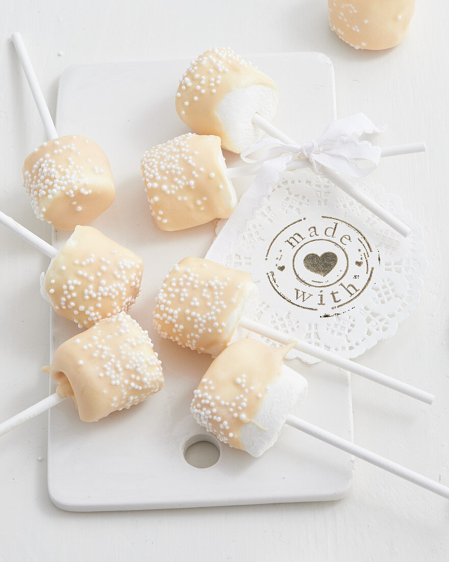 Marshmallows on sticks with white chocolate and sugar sprinkles