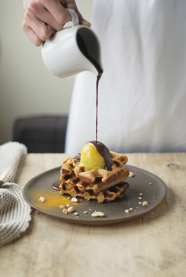 Woman pouring chocolate sauce on waffles