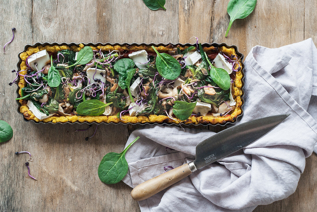Polenta tart with mushrooms, spinach leaves, goat's cheese and sprouts