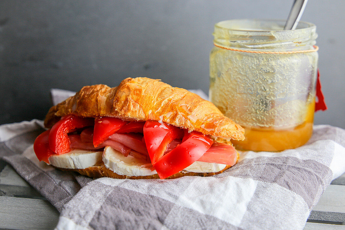 A croissant with red pepper, ham and cheese