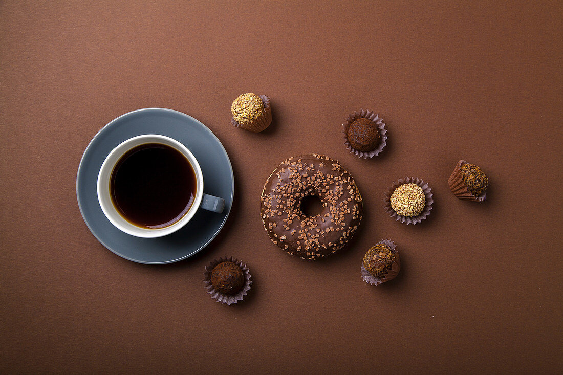 Chocolate donuts with truffles and cup of black coffee