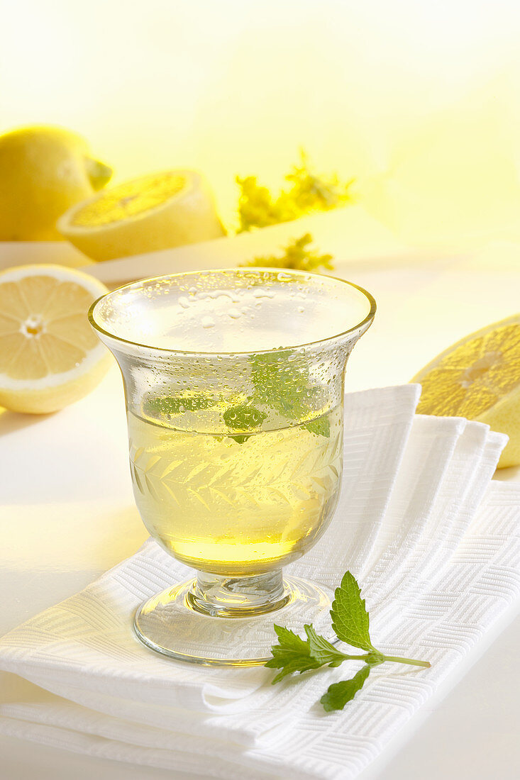 A glass of homemade limoncello with fresh lemons on a napkin