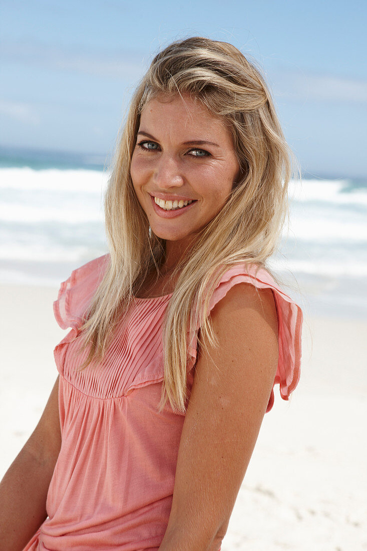 A young woman on a beach wearing a pink top