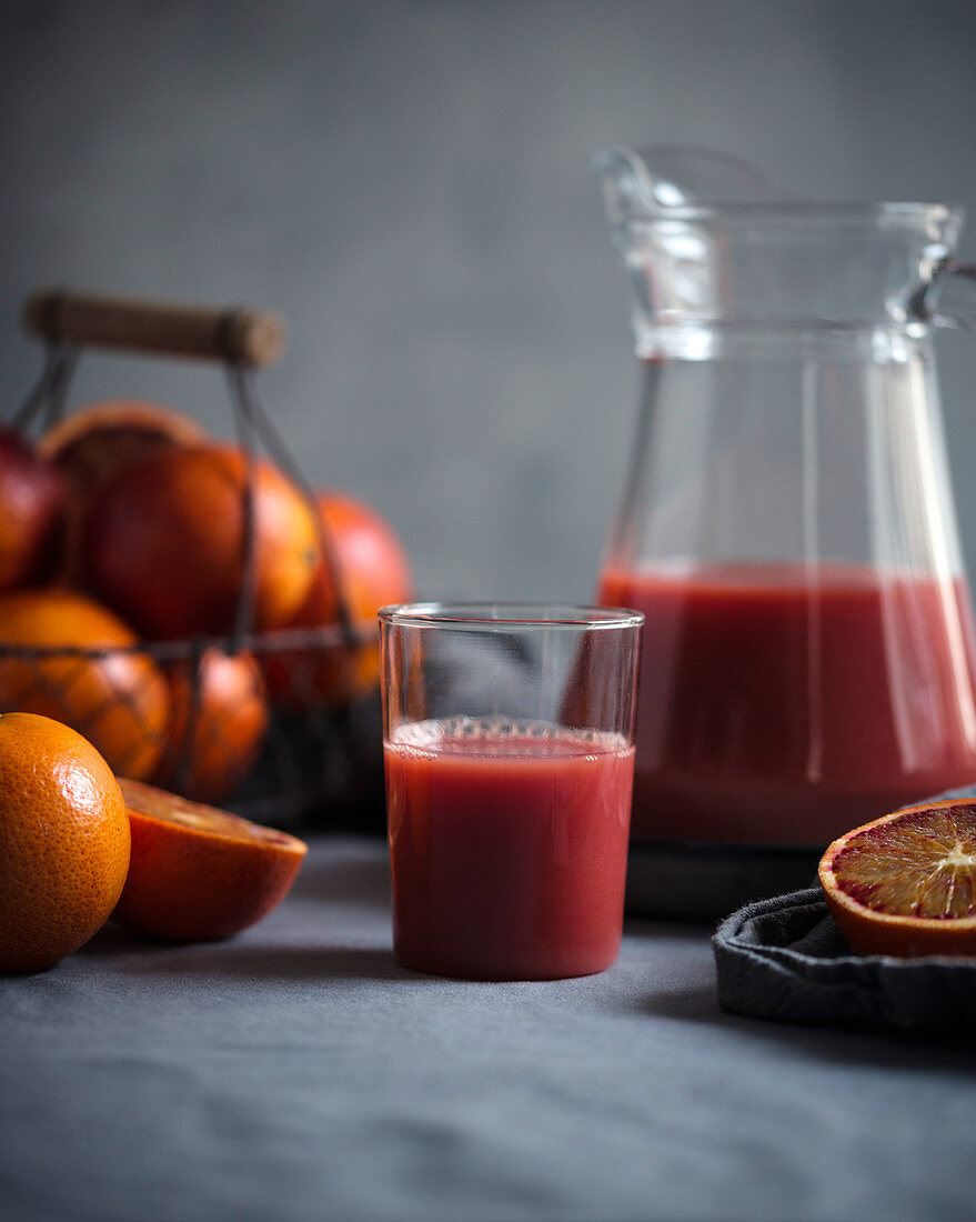 Orangen-Blutorangen-Saft in einer Glaskanne mit frischen Früchten