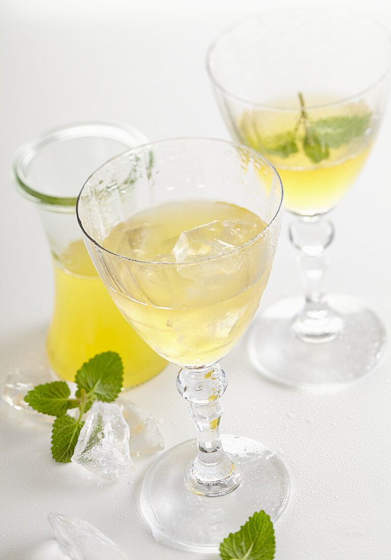 Homemade kiwi liqueur with ice, mint and vodka