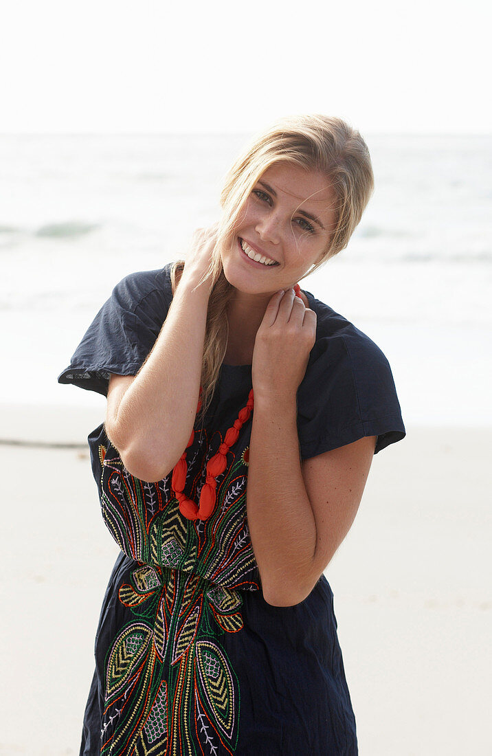 A young blonde woman with necklace wearing a beach dress