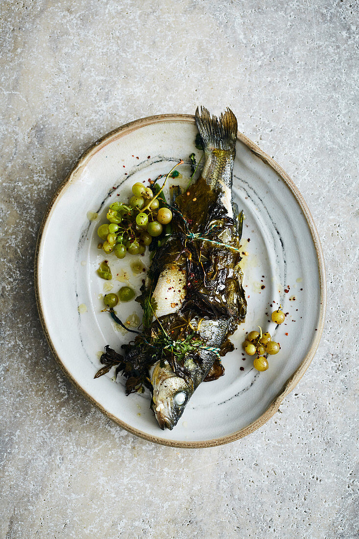 Bass wrapped in vine leaves with grapes