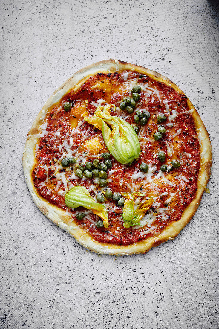 A pizza topped with courgette flowers, capers and pecorino