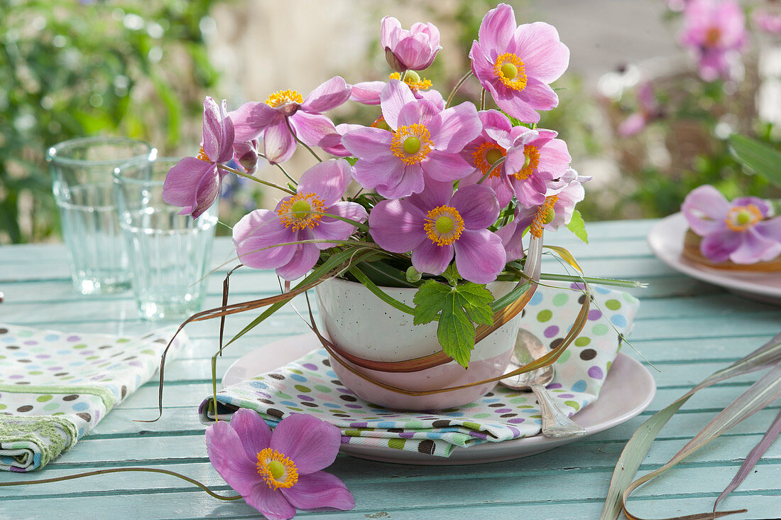 A small bouquet of autumn anemone 'Septembercharme' in a cup